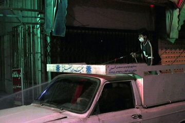 «علیرضا - ۲۱ ساله» در حال ضدعفونی کردن پیادروی یکی از خیابان‌های اصلی شهر آمل