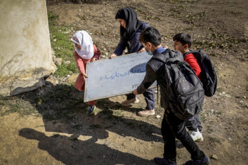 بچه های دبستان آزادی تابلو مدرسه را برای نصب حمل می کنند.