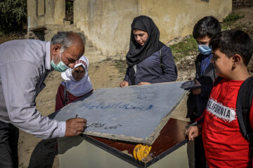 اقای اسعدیان و دانش آموزان تابلوی مدرسه را آماده می کنند.