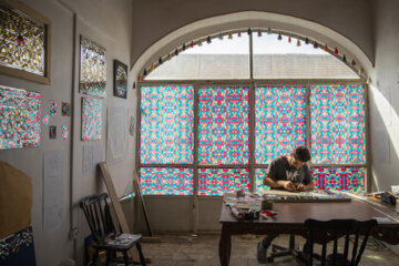 میثم صفری در حجره ای در سرای کتاب فروش های بازار اراک کار آئینه کاری سنتی انجام می دهد.