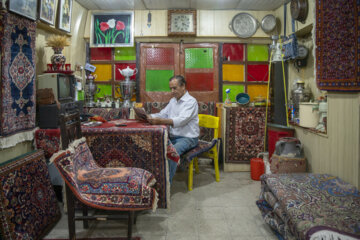 محمدباقر روزبهانی در سرای نوذری بازار ارک کار رفوگری فرش انجام می¬دهد.