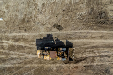 بیل مکانیکی در حال مسطح کردن لای جمع آوری شده از داخل کانال