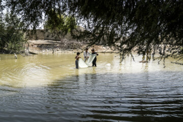 کودکان در روستای سندمراد مشغول تفریح و بازی و همچنین در تلاش هستند که با تور ماهی بگیرند 