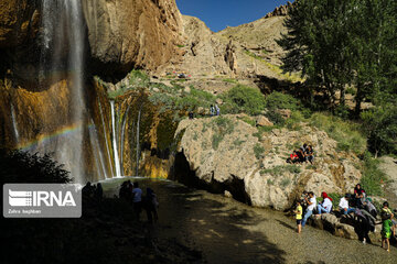 Tourists visiting cool waterfall in central Iran