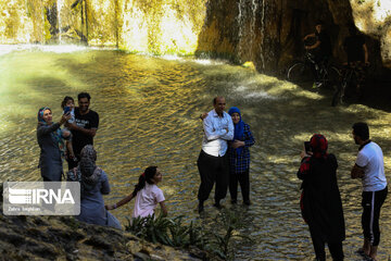 Tourists visiting cool waterfall in central Iran