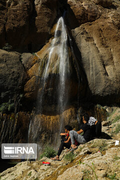 Tourists visiting cool waterfall in central Iran