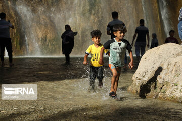 Tourists visiting cool waterfall in central Iran