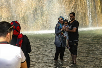 Tourists visiting cool waterfall in central Iran