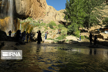 Tourists visiting cool waterfall in central Iran