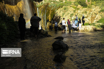 Tourists visiting cool waterfall in central Iran